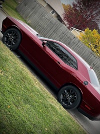 a red dodge challenger parked in a grassy area